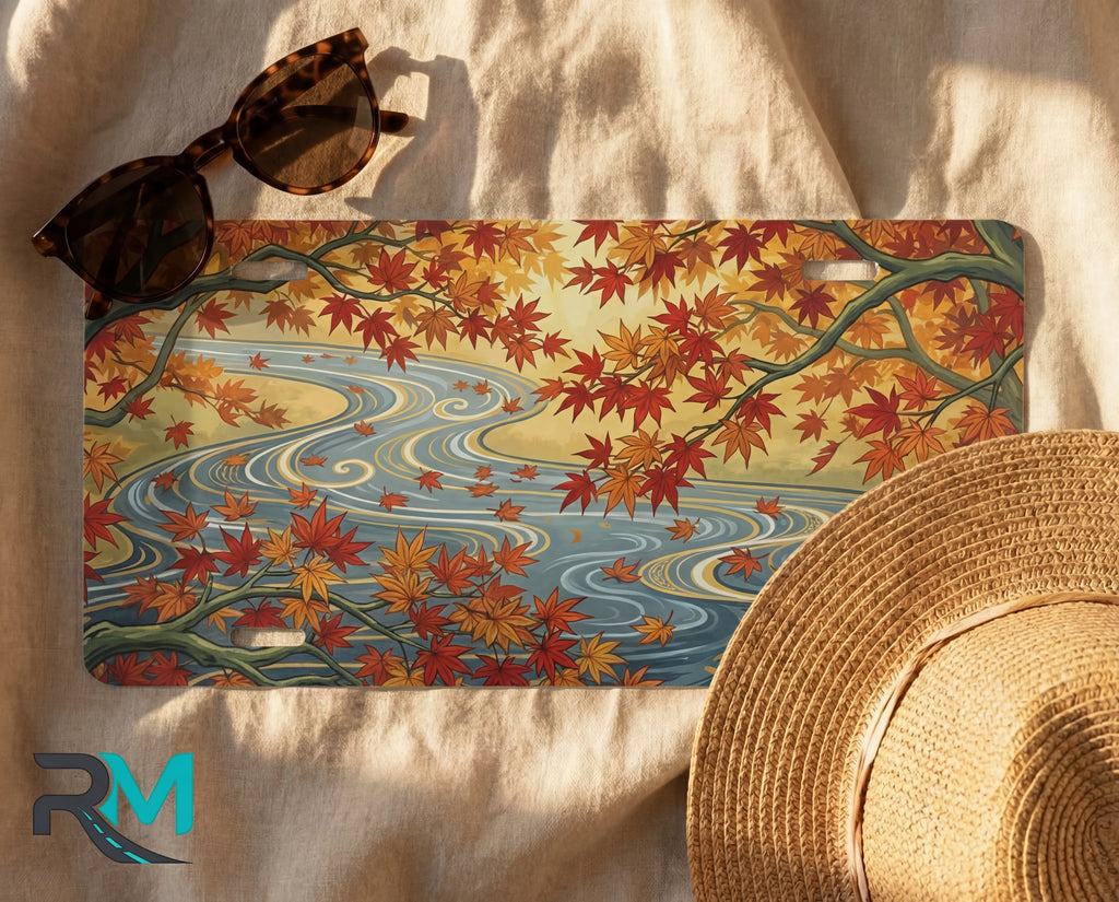 autumn maple stream license plate flat lay — warm orange gold maple leaves winding river soft blue front plate