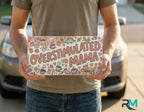 person holding overstimulated mama collage license plate — pastel mom humor vanity plate art