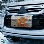 highland cow vanity plate on car in snowy setting — warm ochre lavender pastoral design