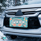 swim mom license plate on car in snowy setting — teal coral goggles swim design