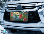 hummingbird hibiscus license plate on car in snowy setting — vivid tropical red emerald design