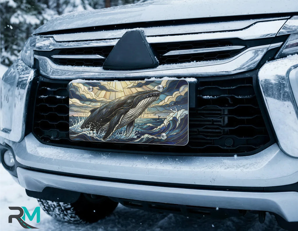 whale surfacing license plate on car in snowy setting — dramatic ocean blue gold whale design