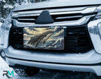 whale surfacing license plate on car in snowy setting — dramatic ocean blue gold whale design
