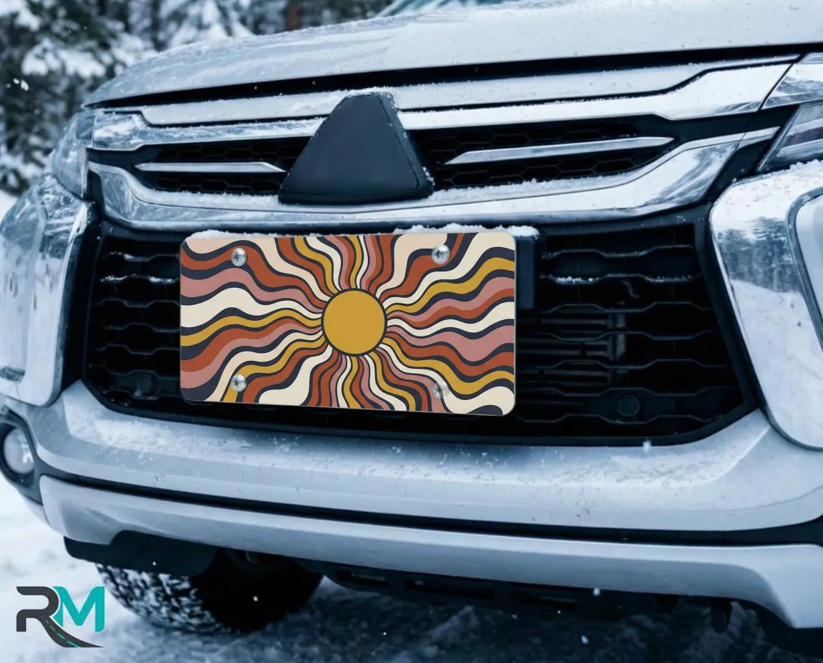 boho sun license plate on car in snowy setting — retro wavy sunburst design