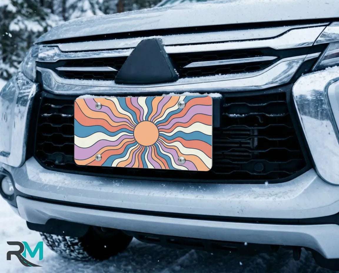retro sunburst license plate on car in snowy setting — colorful boho sunset design