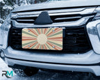 earth tone sunburst license plate on car in snowy setting — retro monogram circle design