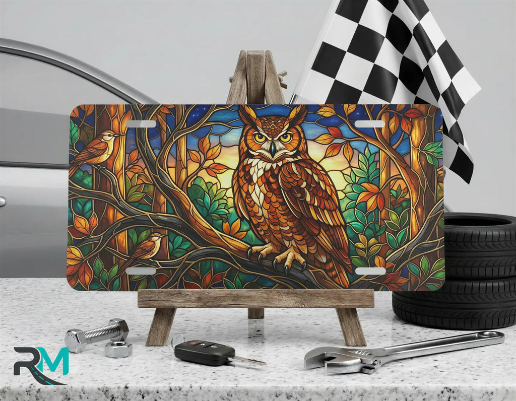 stained glass owl vanity plate on display stand — warm amber forest green twilight aluminum plate